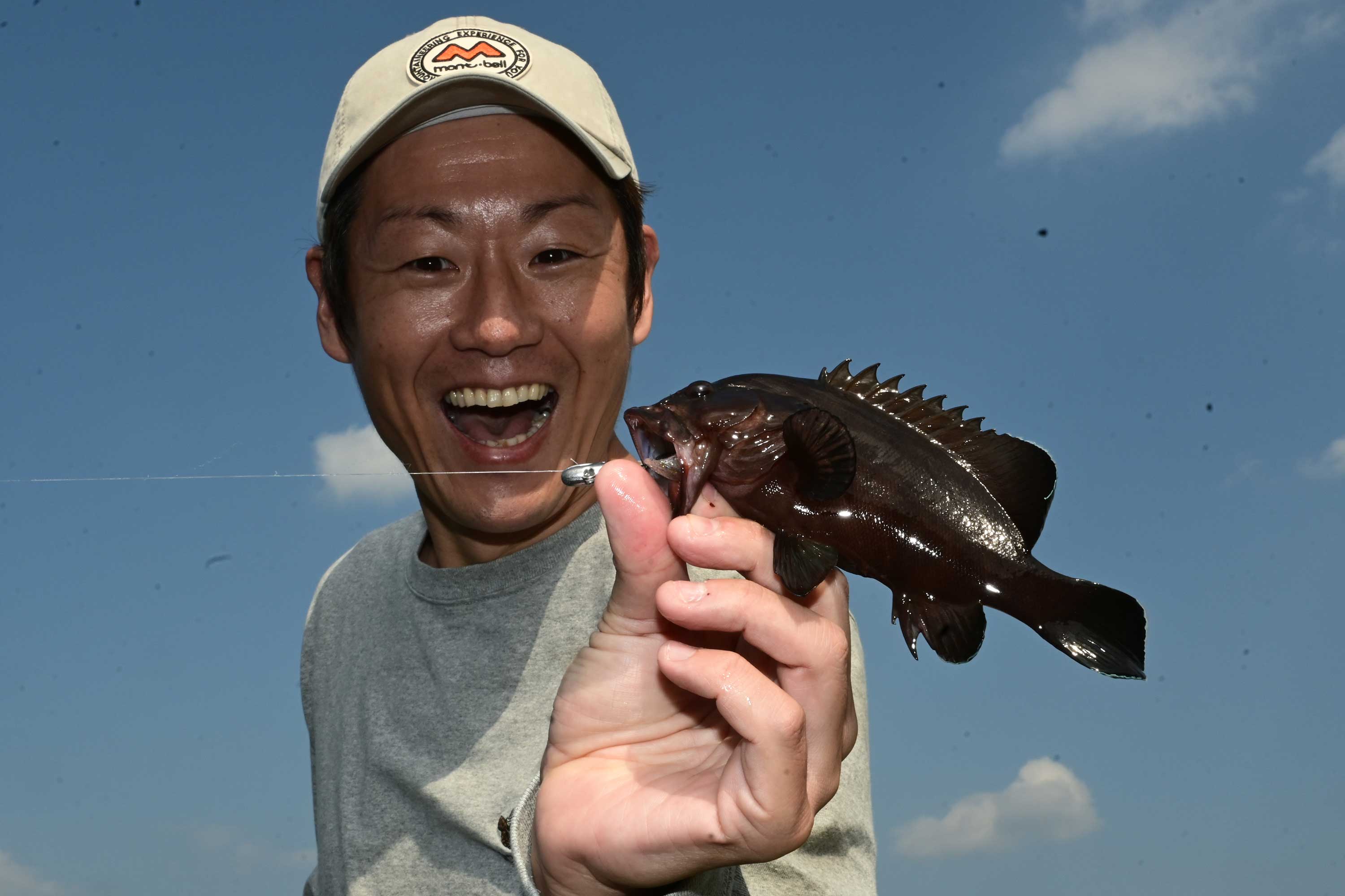 釣り上げた魚を持ち笑顔の男性社員